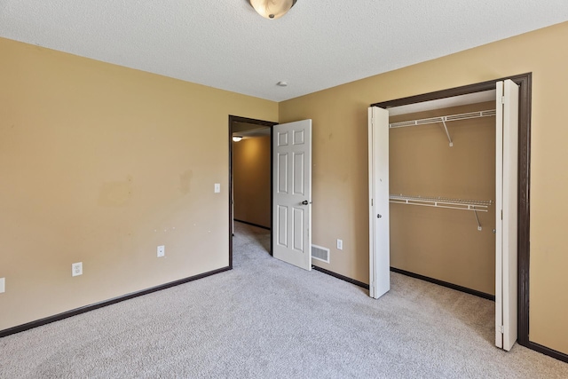 unfurnished bedroom with light carpet, a textured ceiling, and a closet