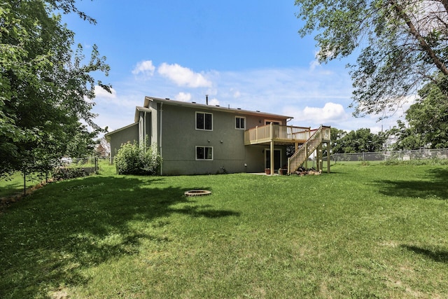 rear view of property featuring a yard, a deck, and an outdoor fire pit