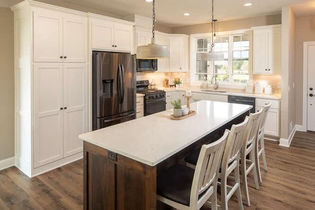 kitchen with black appliances, dark hardwood / wood-style flooring, a center island, pendant lighting, and white cabinets