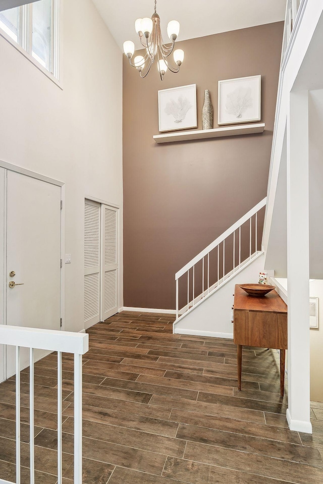 entryway with dark wood-type flooring, high vaulted ceiling, and a chandelier