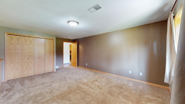 unfurnished bedroom with light colored carpet and a closet