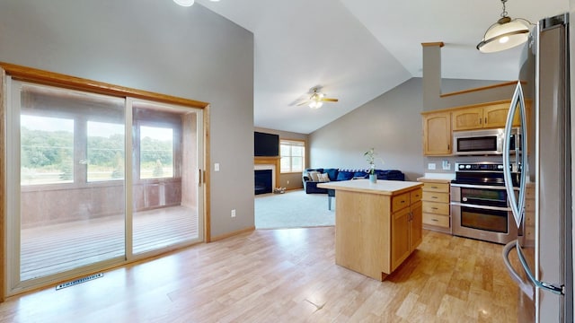 kitchen with light wood-style flooring, a fireplace, light countertops, appliances with stainless steel finishes, and light brown cabinetry