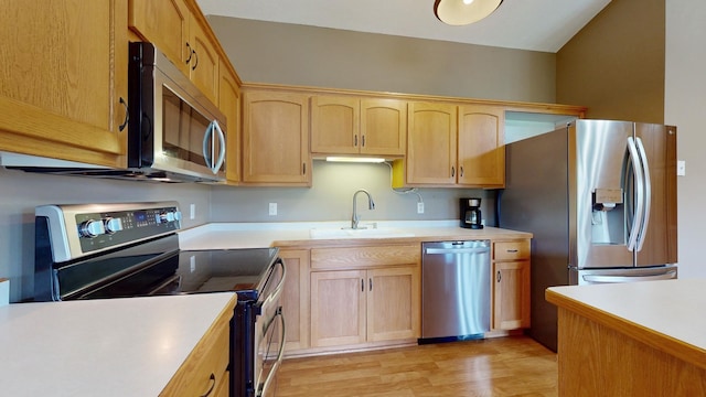 kitchen featuring stainless steel appliances, light countertops, light wood-style floors, light brown cabinets, and a sink