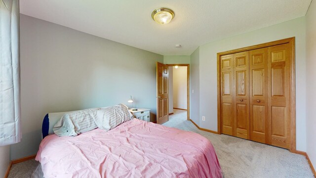 bedroom featuring a closet, light carpet, and baseboards