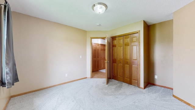 unfurnished bedroom featuring light carpet, baseboards, and a closet