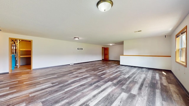 empty room featuring wood finished floors, visible vents, and baseboards