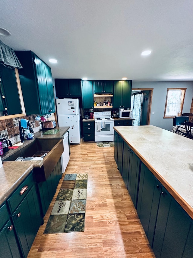 kitchen with tasteful backsplash, white appliances, sink, and light hardwood / wood-style floors