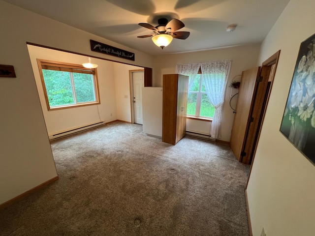 unfurnished bedroom with a baseboard heating unit, multiple windows, light colored carpet, and ceiling fan