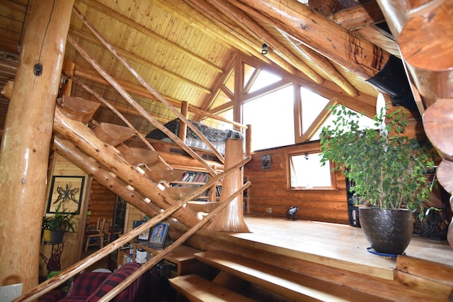 staircase with hardwood / wood-style floors, lofted ceiling with beams, log walls, and wood ceiling