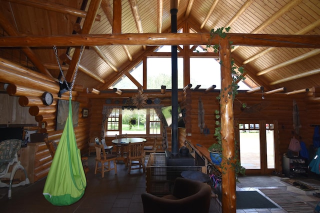 living room featuring a wood stove, log walls, and high vaulted ceiling