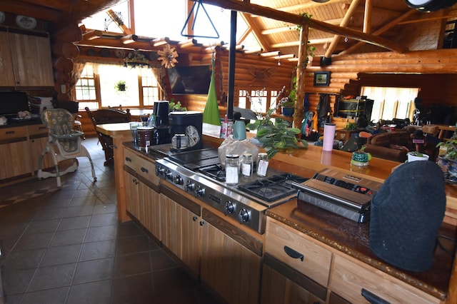 kitchen featuring vaulted ceiling with beams, log walls, stainless steel gas cooktop, and dark tile patterned floors