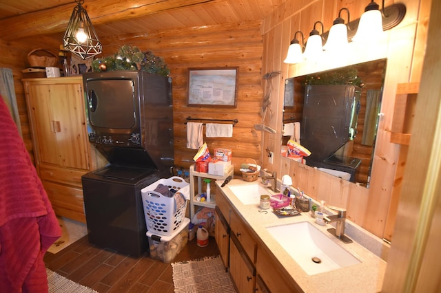 bathroom featuring stacked washer / dryer, vanity, wood walls, and wood finished floors