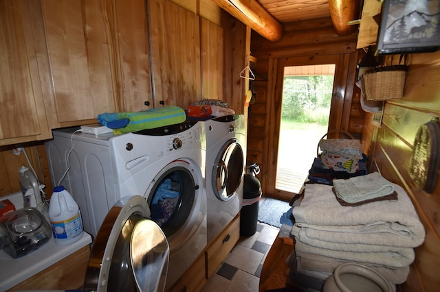 clothes washing area featuring log walls, separate washer and dryer, cabinets, and tile patterned floors