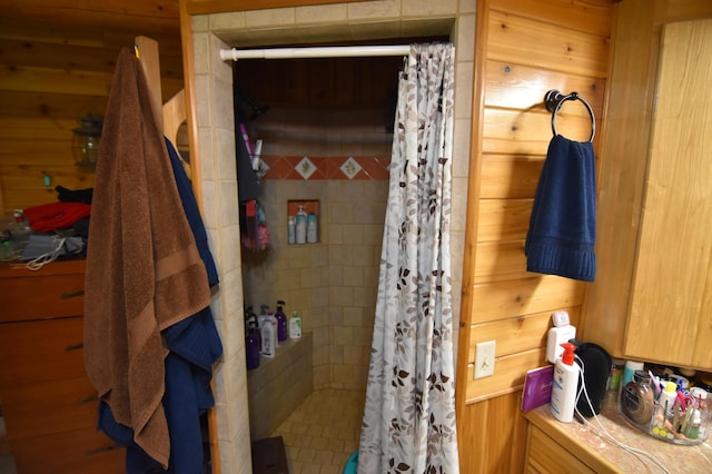 bathroom with wood walls and a stall shower