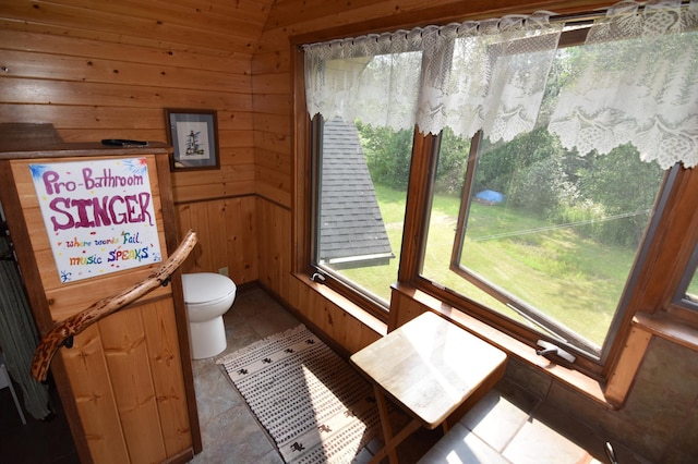 bathroom featuring tile patterned flooring, toilet, and wooden walls