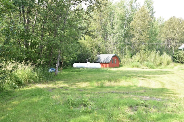 view of yard featuring an outbuilding, a view of trees, and a barn