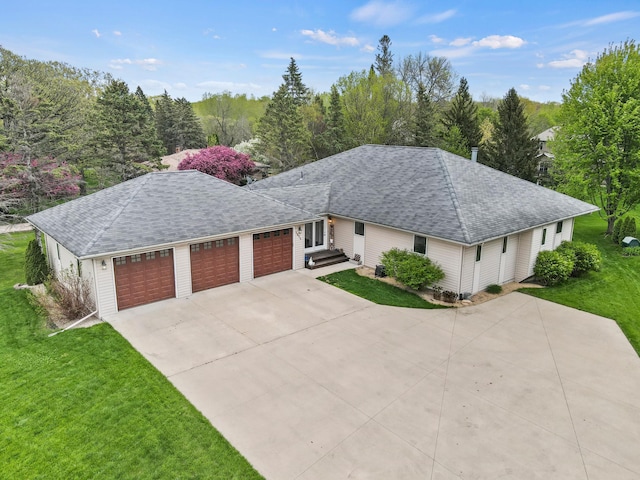 ranch-style house featuring a garage, roof with shingles, concrete driveway, and a front lawn