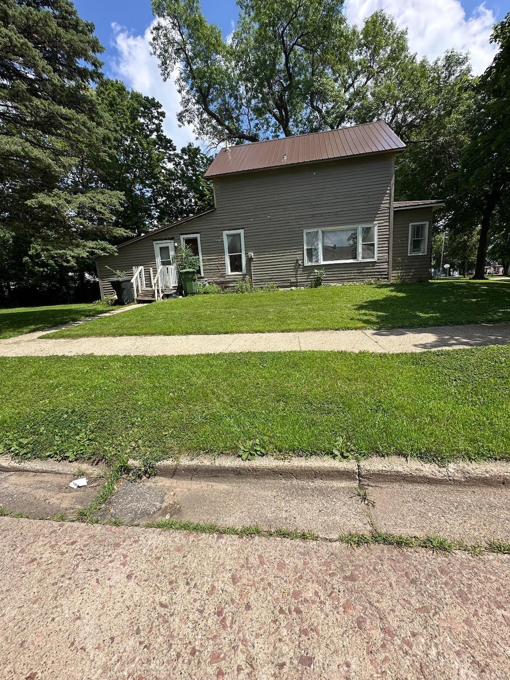 view of front facade featuring metal roof and a front yard