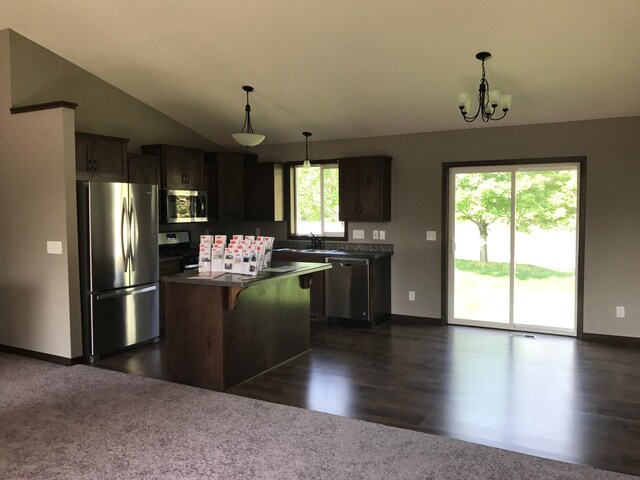 kitchen featuring a notable chandelier, a center island, dark wood-type flooring, stainless steel appliances, and vaulted ceiling