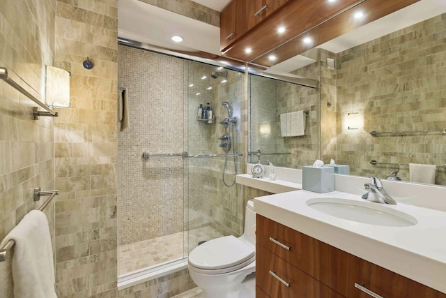 bathroom with tile walls, vanity, toilet, and walk in shower