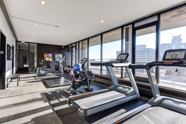 exercise room with a city view, floor to ceiling windows, and recessed lighting