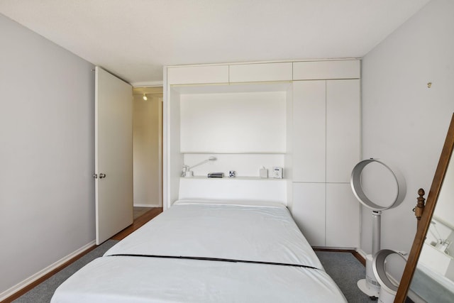 bedroom featuring baseboards and dark carpet