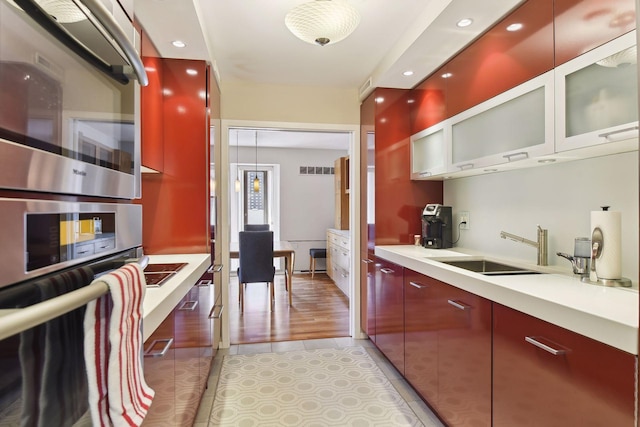 kitchen with sink, stainless steel oven, and light hardwood / wood-style floors