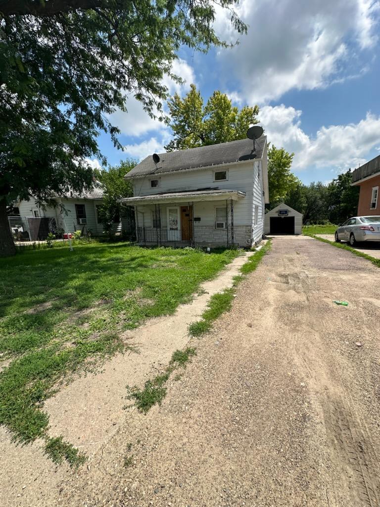 rear view of property featuring a lawn, an outbuilding, and covered porch