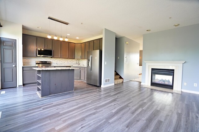 kitchen featuring appliances with stainless steel finishes, pendant lighting, and hardwood / wood-style flooring