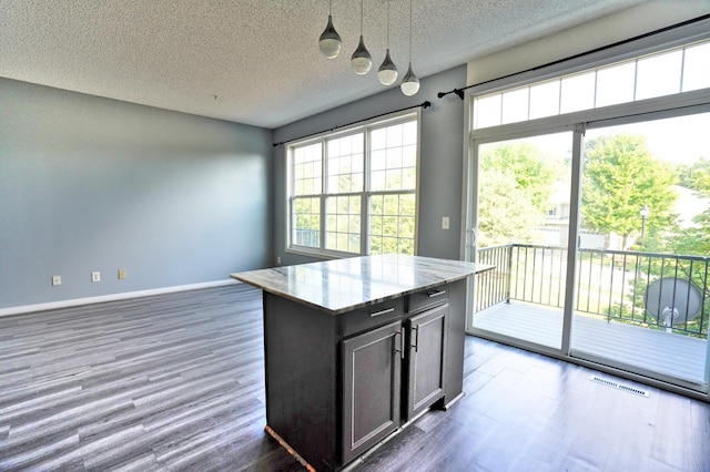 kitchen featuring a kitchen island, pendant lighting, a textured ceiling, and dark wood-type flooring