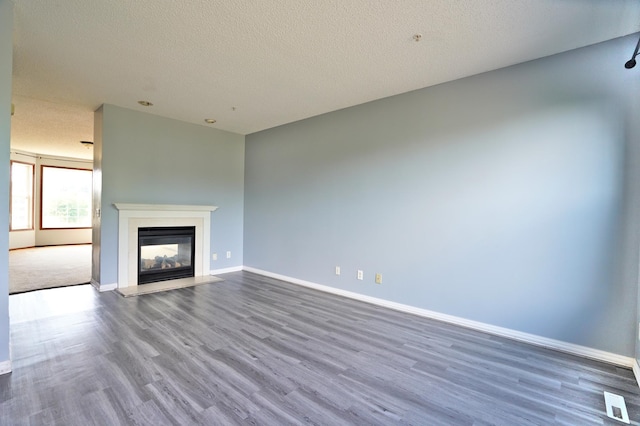 unfurnished living room featuring a multi sided fireplace, hardwood / wood-style flooring, and a textured ceiling