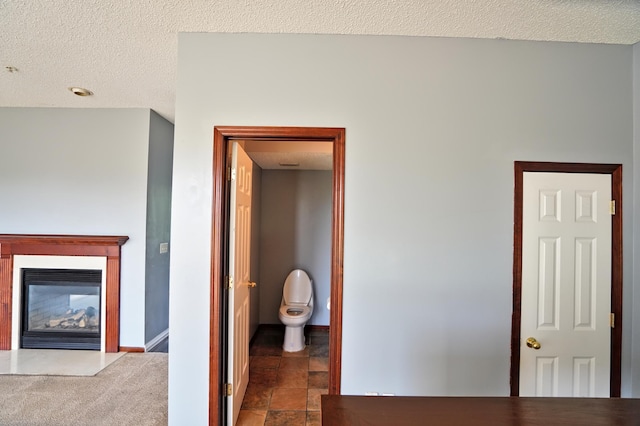 hall with a textured ceiling and dark tile patterned floors