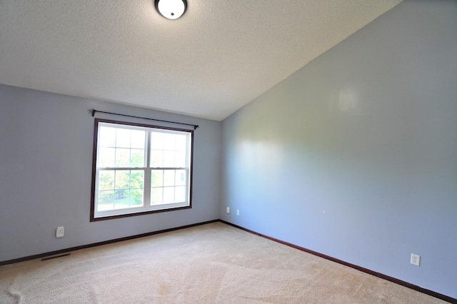 empty room featuring vaulted ceiling, carpet, and a textured ceiling