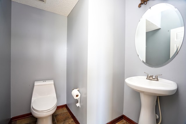 bathroom featuring tile patterned floors, a textured ceiling, and toilet