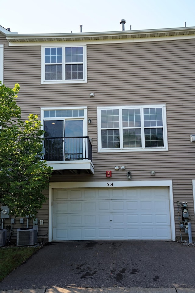 view of front of home featuring a balcony, a garage, and central AC