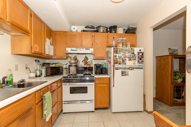 kitchen with white appliances, sink, a textured ceiling, and light tile patterned floors