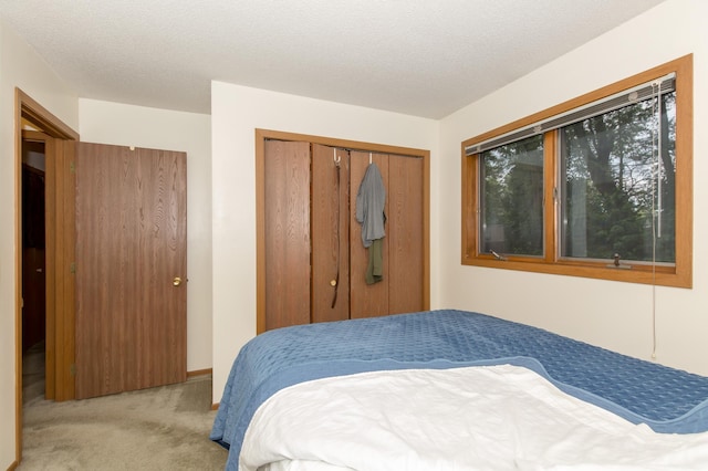 bedroom featuring light carpet, a textured ceiling, and a closet