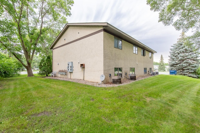 view of side of home with central AC and a lawn