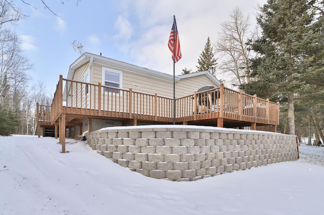 snow covered back of property with a wooden deck