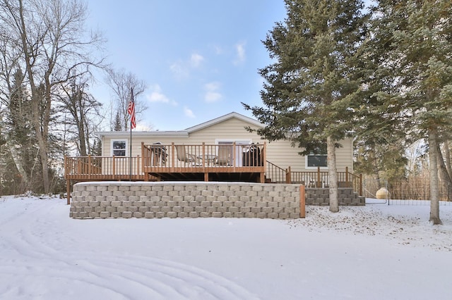 snow covered back of property with a deck