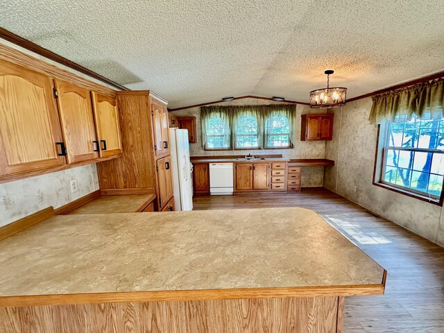 kitchen with lofted ceiling, white appliances, a healthy amount of sunlight, and a notable chandelier