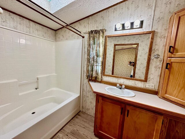 bathroom featuring washtub / shower combination, wood-type flooring, vanity, and a textured ceiling