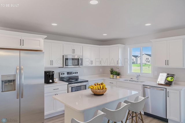 kitchen with a kitchen island, appliances with stainless steel finishes, sink, and white cabinets