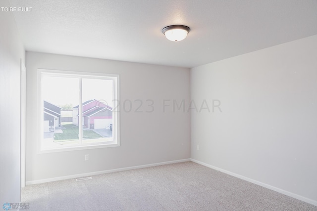 carpeted spare room with a textured ceiling