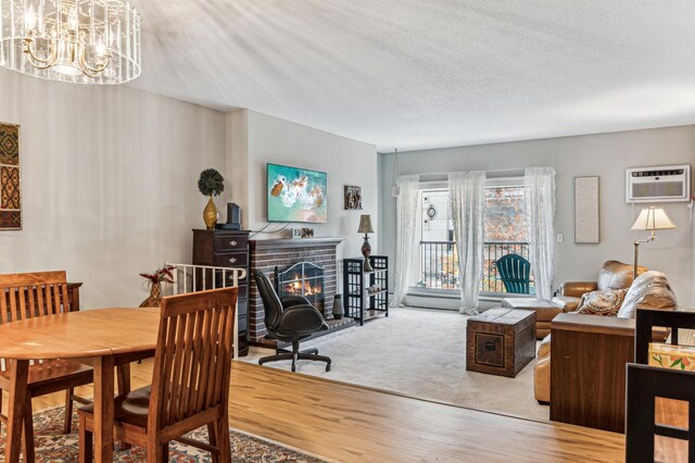 carpeted dining space with a wall mounted AC, a brick fireplace, a chandelier, and a textured ceiling