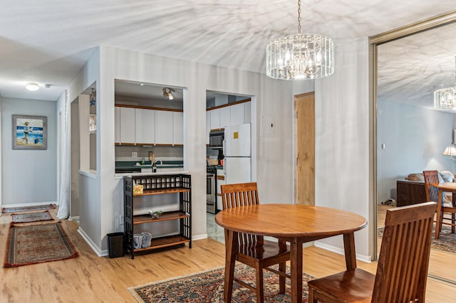 dining room featuring an inviting chandelier, a textured ceiling, baseboards, and wood finished floors