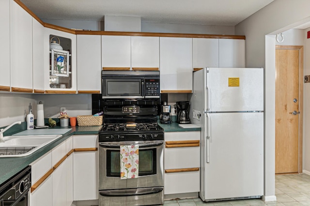 kitchen featuring black appliances, dark countertops, a sink, and white cabinets