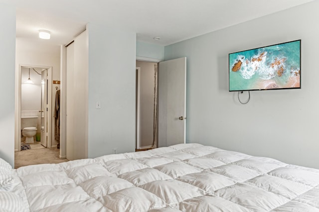 bedroom with connected bathroom and light colored carpet