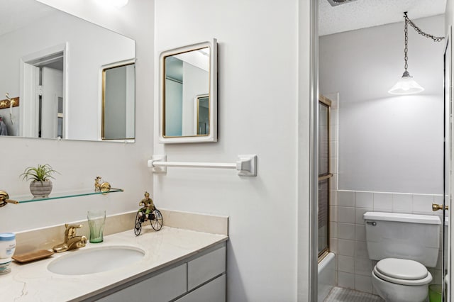 bathroom featuring tile walls, toilet, enclosed tub / shower combo, vanity, and a textured ceiling