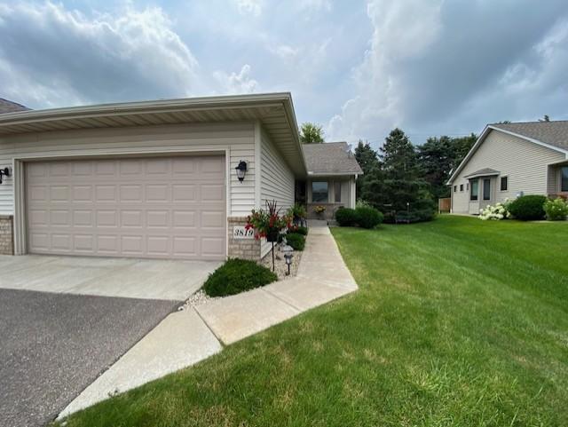 view of front of property featuring a front yard, a garage, brick siding, and driveway